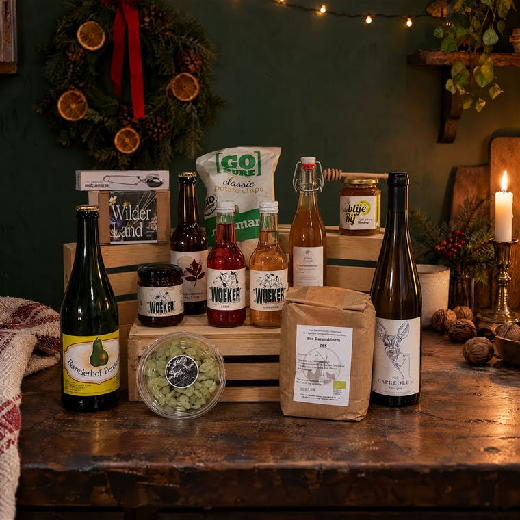 Groot kerstpakket met wijn, perensap, meel, honing en jam, bij kaarslicht