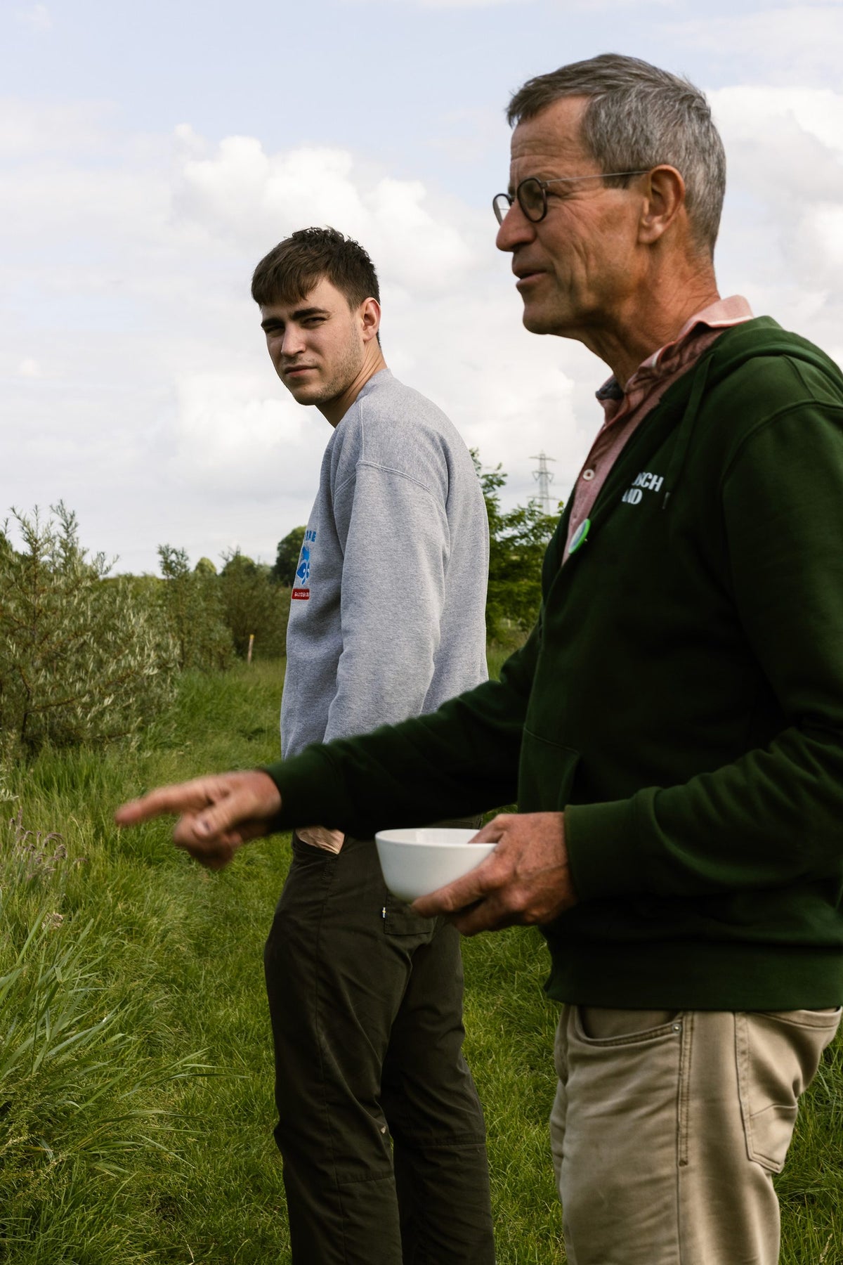 Uitleg en een kom vol oogst tussen de jonge bomen van het voedselbos